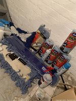 Photo showing four blue mop heads, mop frame, four rolls of Scott Shop Original towels, cans of glass cleaner and a spray bottle.