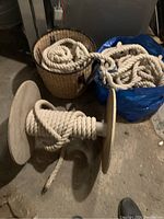 Thick white cotton rope wound around a large white spool and additional rope coiled beside a woven basket on the floor.