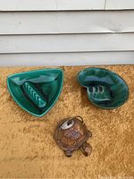 Three Matt Mid Century ashtrays: two ceramic with green glaze and one carved wooden turtle ashtray.