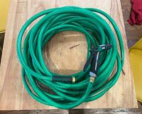 Photo showing the entire coiled green garden hose with nozzle