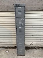 Front view of six metal locker doors with ventilation slots and a lock on the second door from the top.