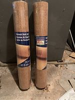 Two sealed rolls of natural cork standing upright, with labels showing measurements and branding visible.