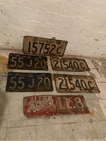 Six vintage items: five old Ontario licence plates and one section of an old hand painted metal sign, all showing rust and wear.