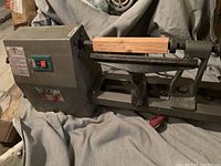 Full view of wood turning lathe showing headstock, tool rest, tailstock with wood blank