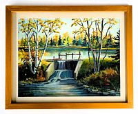 Framed landscape oil painting showing a dam with water flow, surrounded by trees with autumn leaves, in a wooden frame with glass and matting.