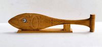 Full view of wood carving fish paddle mounted on stand, showing overall shape and details