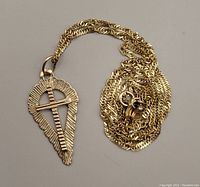 Full view of gold necklace chain and cross pendant laid flat on grey background