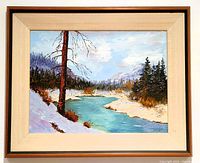 Framed oil on board painting showing the full riverside landscape scene with snow, trees, and mountains.