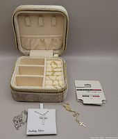Two religious pendant sterling silver necklaces displayed with zippered velvet storage box, packaging and tags visible.