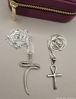 Photo of two sterling silver necklaces: one with a large crystal-studded stylized cross pendant and new 30" chain, the other with a sterling silver ankh pendant on an 18" chain. Velvet zippered box in background.