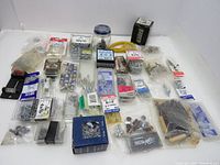 Full array of various new screws, washers, mirror clips, and fasteners spread on a white surface.