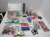 Full view of lot on table including various bags and containers of beads, sequins, patches, and pom-poms.