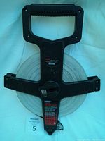 Front view showing plastic handle and spool holding the large fiberglass tape with label for 200 ft measurement and Empire branding