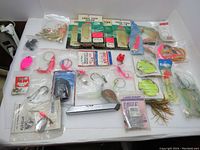Wide view of the 32 bags of fishing lures and tackle including assorted colors and types of fishing lures, hooks and bobbers, displayed on white surface
