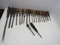Photo showing full set of 22 wooden handle screwdrivers arranged in a line, varying sizes and colors, both flathead and Phillips types.