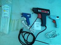 Photo showing all three glue guns and assorted glue sticks including packaged and loose sticks.