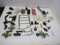 Full lot overview showing various vintage brass hardware including drawer pulls, window openers, door stoppers, decorative plates, and other assorted pieces spread out on white background.