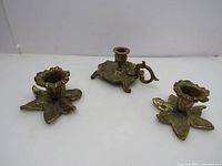 Three vintage brass candle holders in a group with visible patina and used condition.