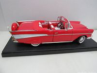 Side angle view of the red and white 1957 Chevrolet Bel Air convertible die-cast model on black display base showing detailed chrome trim and whitewall tires.