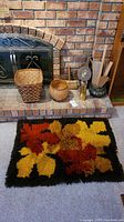 Photo of two woven baskets, fireplace tools, and handwoven rug in front of brick fireplace