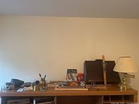 Wide view of a wooden credenza holding the camera, phone, lamp, briefcase, brass ink holder, and other small items