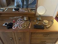 Overview of all items on the wooden cabinet including belts, mirror, watch, and small boxes.