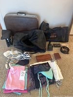 Full view of entire lot: brown Birkdale suitcase, black Harley Davidson duffle bags, scarves, wool socks, belt, and leather accessories on carpeted floor.