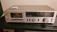 Front view of Technics stereo cassette receiver with cassette inserted in play position showing controls and VU meters.