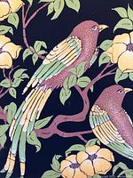 Close-up detail of batik fabric artwork showing two perched birds among green leaves and yellow flowers on black background, demonstrating fabric color and texture.