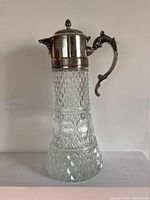 Front angle showing the diamond and circle pressed glass design and ornate silver plated lid and handle with spout