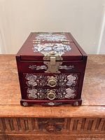 Front view showing intricate mother of pearl inlay of squirrels and grapevine, brass latch and drawer pulls on the lacquered rosewood box.