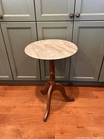 Full view of the round marble tabletop and three wooden legs.