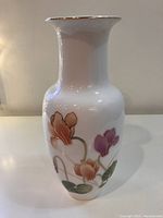 Front profile view of white vase showing purple and pink flowers with gold outlines and green leaves.
