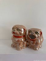 Front view of vintage pug dog cream pitcher and sugar bowl, showing high-gloss peach lustre finish and detailed painted facial features.