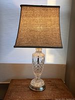 Full view of the tall pressed glass lamp on wooden surface highlighting shape and shade.