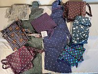 Ten aprons of mixed bib and waist styles with various geometric and floral patterns laid out