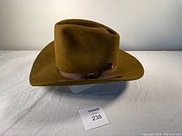 Brown 5X Beaver felt cowboy hat with long oval shaped, hand creased crown, brown grosgrain hatband and feather decoration on side.