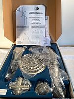 Open box showing all components of the shower kit packaged in molded tray resting in a box with instruction sheet and assembly guide visible.