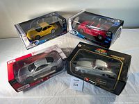 Four 1:18 scale diecast model cars in original packaging including Mercedes and Porsche models.