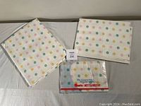 Duvet cover and fabric piece laid out with polka dot pattern visible, white background with pastel dots in green, pink, yellow, and blue.