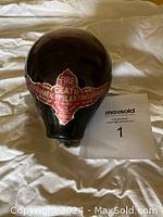 Photo of the spherical dark glass fire extinguisher grenade placed on a cloth surface, showing its overall shape and size.