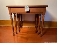 Front view of the largest wooden nesting table showing turned legs and rectangular top.