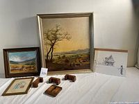 Lot overall photo showing original painting "Harvest" by Dee Lott, framed print, black and white sketch, and four wooden plate display rests on a table.