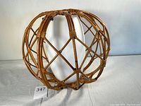 Side view of natural rattan cage with curved and crossed canes in circular shape