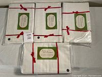 Five vintage white bed sheet sets, each tied with a red string ribbon and original green-white label packaging.