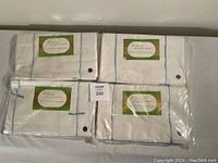 Four packaged vintage white cotton bed sheets with blue stitched borders, tied with blue string, and labeled Embasy Fine Quality Sheets.