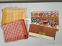 Three tea towels displayed flat showing patterns and labels