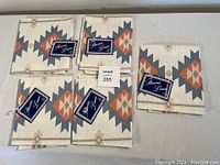 Set of five folded tea towels displaying geometric colored pattern with attached Verene Linen tags.