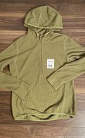 Front view of the olive green Avia fleece hoodie showing fitted style, thumb holes, and hood