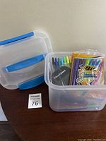 Plastic Sterlite container with lid open showing multiple pens inside including Bic Shimmers and colored felt-tip pens.